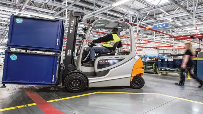 Operator driving a forklift in a factory